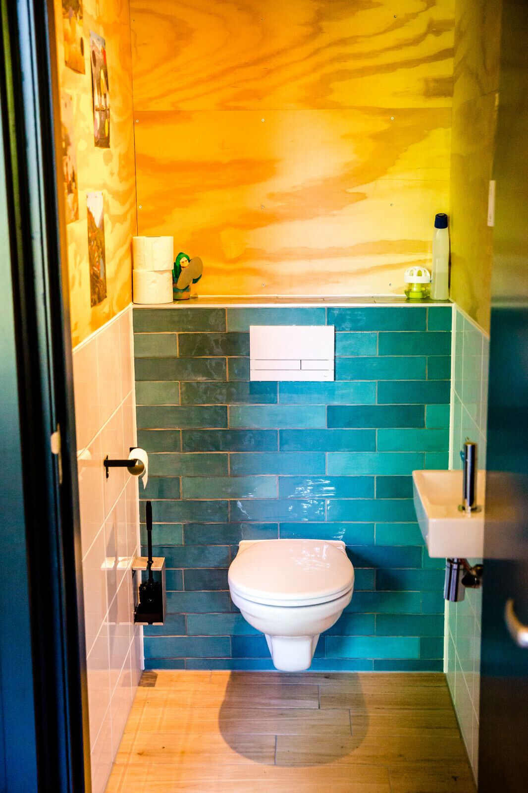 Een kleine badkamer met een toilet, een wastafel en een toiletrolhouder aan de muur.