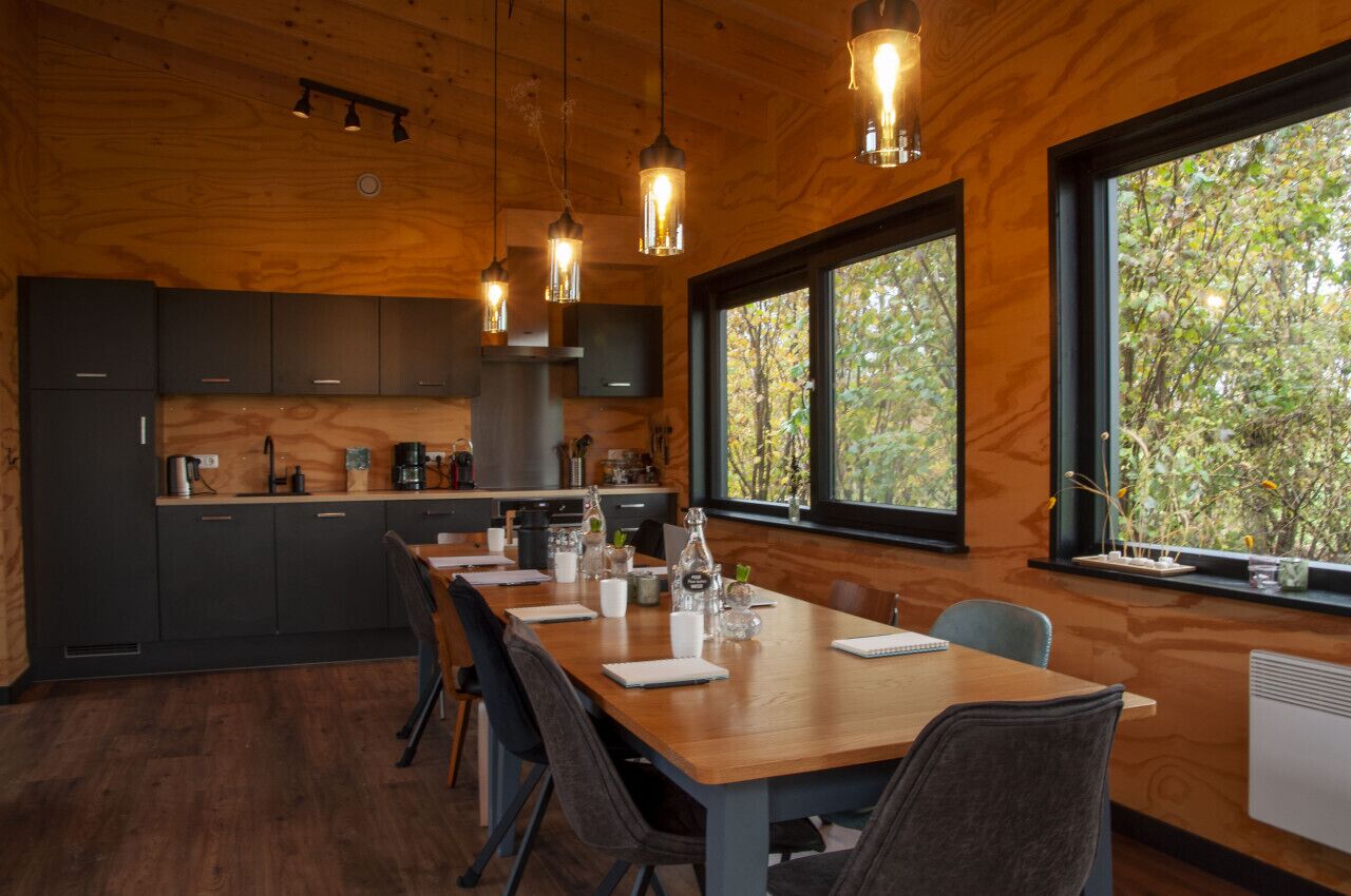 Una cucina moderna con mobili in legno, un lungo tavolo da pranzo e lampade a sospensione.