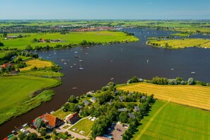 An aerial view of a riverside town with boats, green fields, and houses along the water. - Waterlodge Goudule in Nes (Nes)