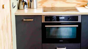 Une cuisine moderne dotée d’un four encastré, d’appareils électroménagers en acier inoxydable et d’un plan de travail en bois.