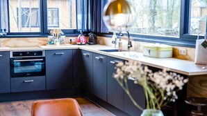 Una cocina moderna con armarios oscuros, encimera de madera y ventana con vistas a árboles.