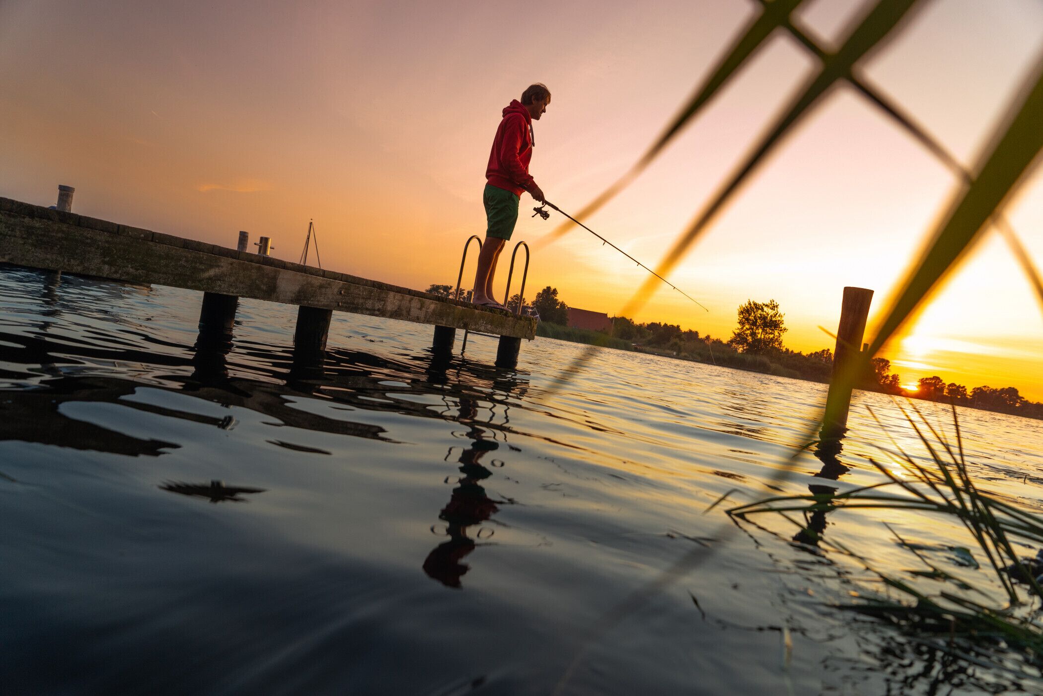 Una persona pescando al moll durant el capvespre.