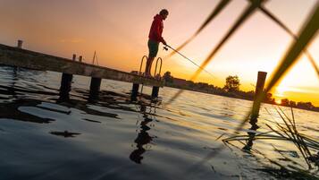 Una persona pescando al moll durant el capvespre.