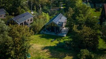 A riverside property with a dock, a boat, and two houses surrounded by greenery.