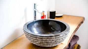 Un baño con un lavabo de cerámica grande y oscuro, un grifo moderno y una encimera de madera.