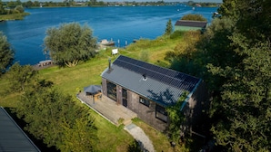 Una cabaña junto al lago con techo de paneles solares, una terraza y vistas al lago.