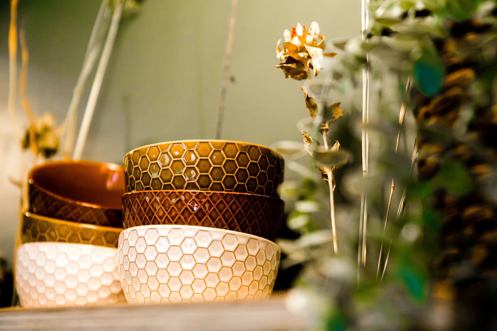 A close-up of three bowls with a honeycomb pattern, placed on a surface with a blurred background of greenery.