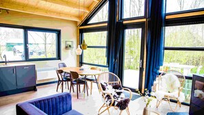 Een modern interieur met een eethoek, een bank en grote ramen.