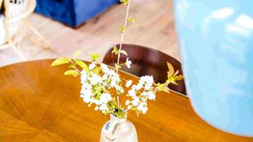A wooden table with a ceramic vase containing white flowers and a smartphone.
