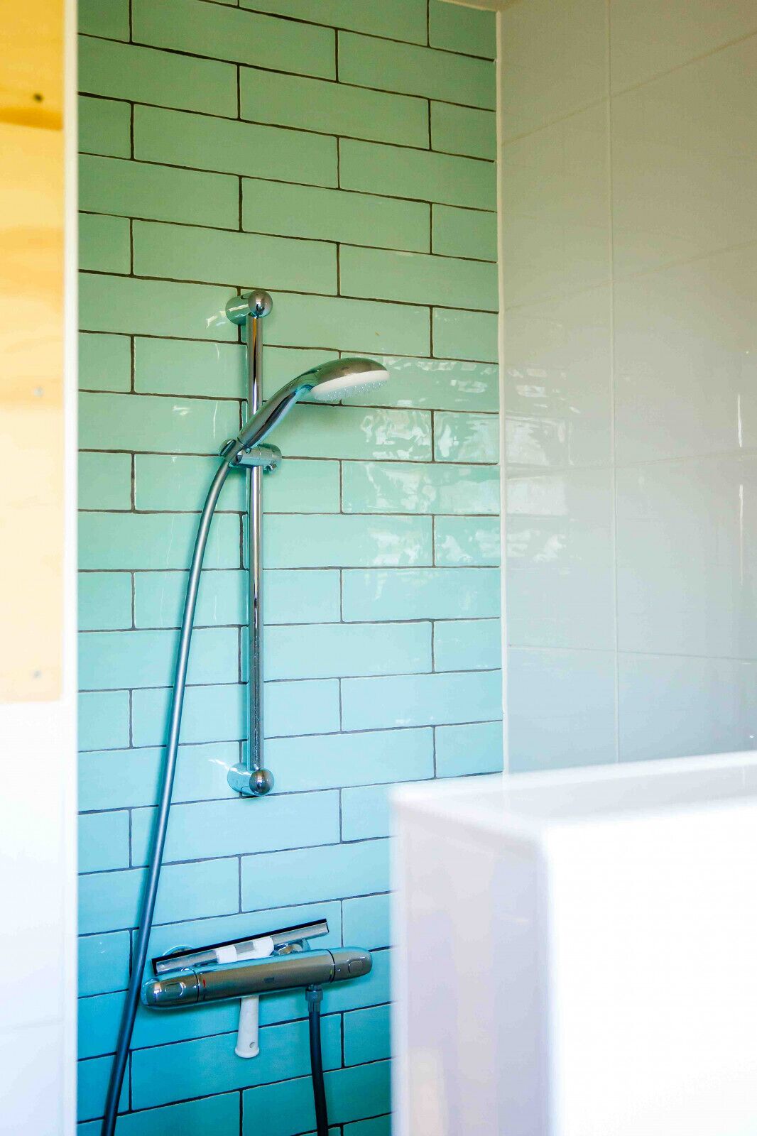 A bathroom with a shower head mounted on a wall with blue tiles.