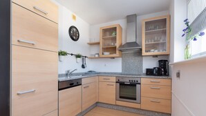 A modern kitchen with wooden cabinets, a built-in oven, and a coffee maker. - Spacious Family Suite | Balcony | 2 Bedrooms (Swinoujscie)