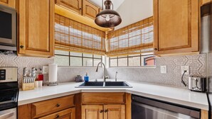 A kitchen with wooden cabinets, a stainless steel dishwasher, and a double sink. - Lakefront Home | Community Pool & Hot Tub (Chandler)