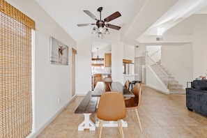 A spacious dining area with a wooden table and chairs, a ceiling fan, and a staircase leading to another level. - Lakefront Home | Community Pool & Hot Tub (Chandler)