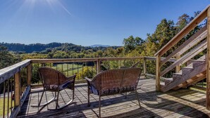 A wooden deck with two wicker rocking chairs and a staircase.