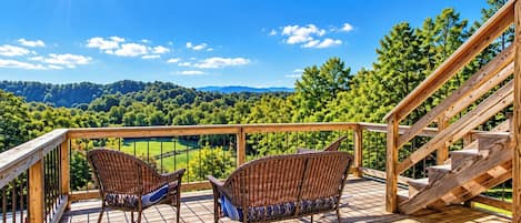 A wooden deck with wicker chairs and a staircase.