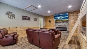 A room with a fireplace, wooden paneling, a mural, and a reclining leather sofa.