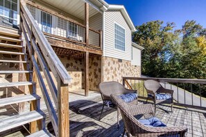A wooden deck with wicker furniture and a stone wall.