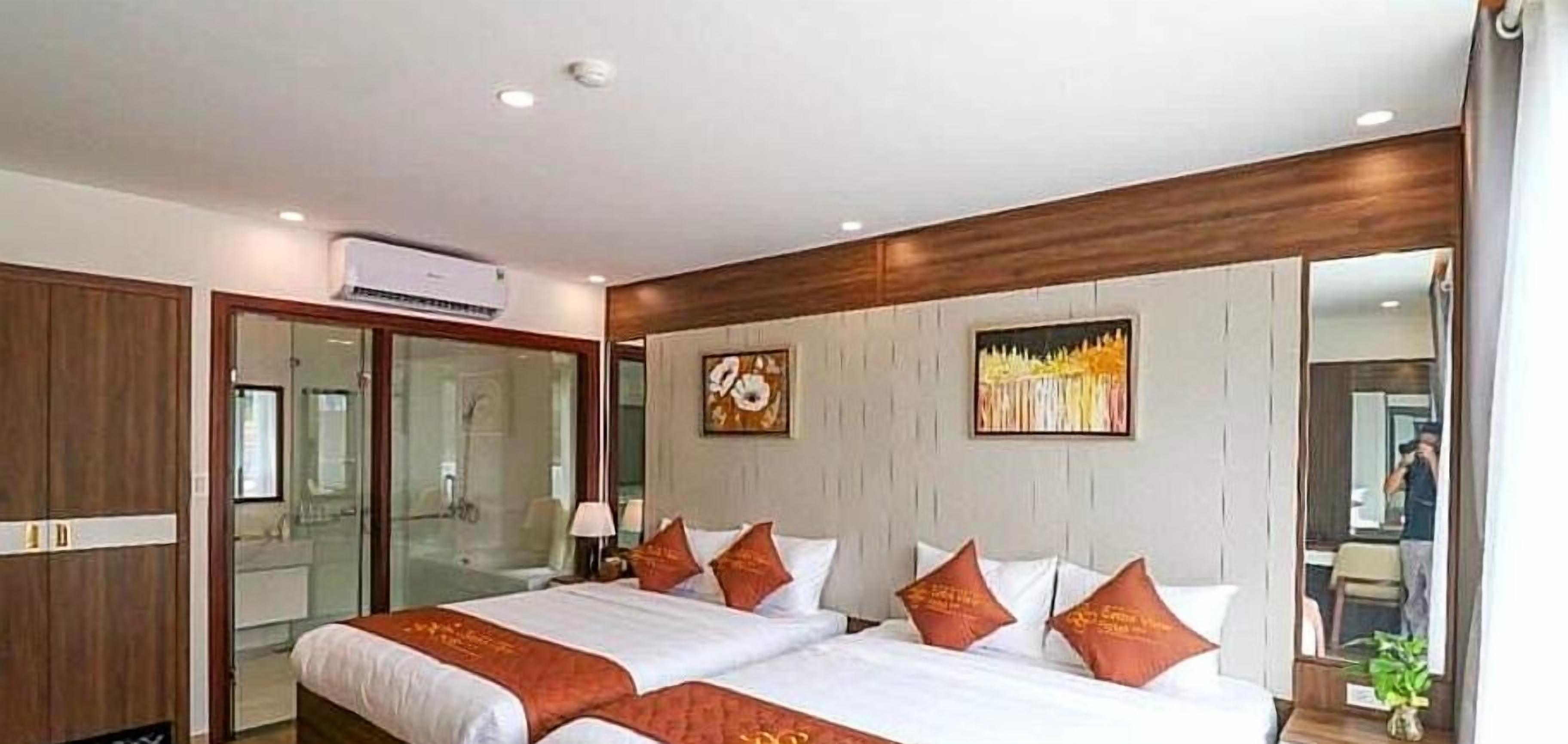 A hotel room with two beds, a large mirror, and a wardrobe.