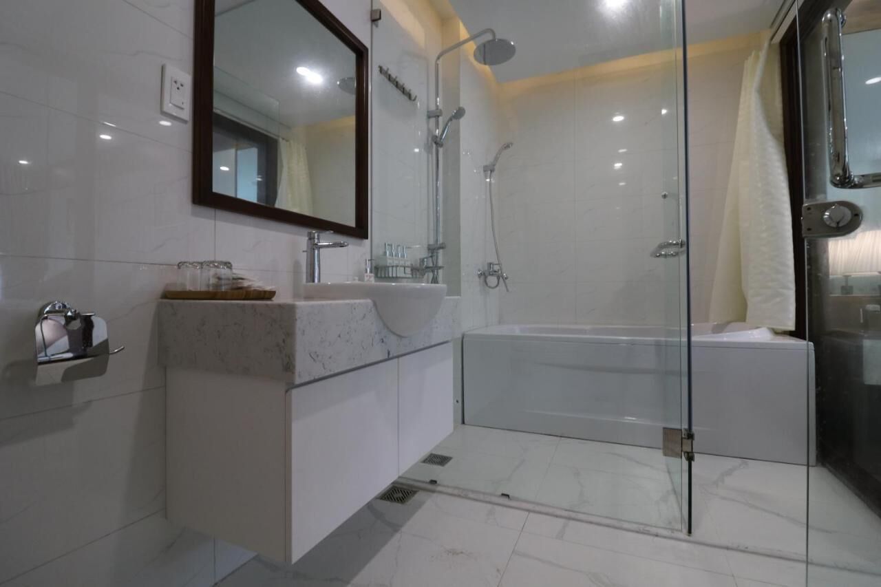 A modern bathroom with a glass-enclosed shower, a large mirror, and a white vanity.