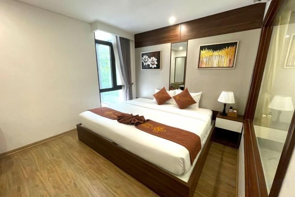 Une chambre d’hôtel avec un grand lit, des tables de chevet, une fenêtre et un tableau au mur.