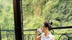 A person sitting on a chair on a balcony with a view of greenery. - Catba View Hotel (Hai Phong)