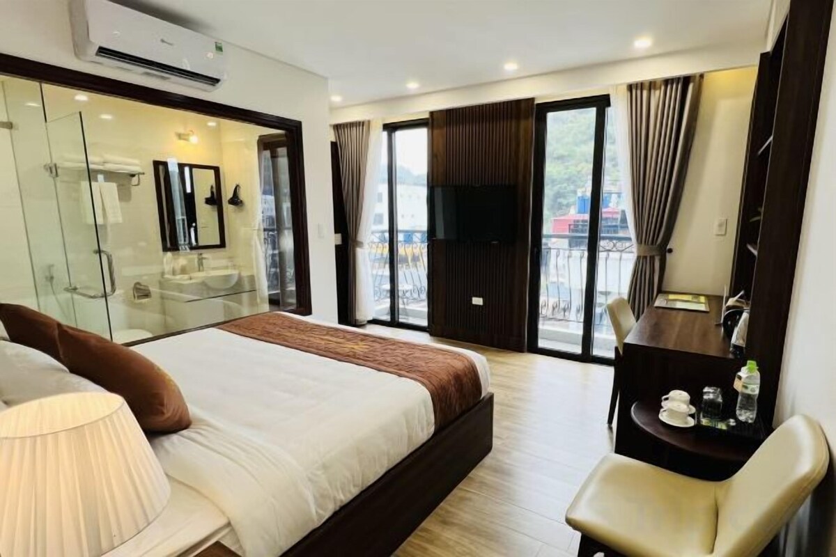 Une chambre d’hôtel avec un lit, un bureau, une chaise, une télévision et un balcon offrant une vue.