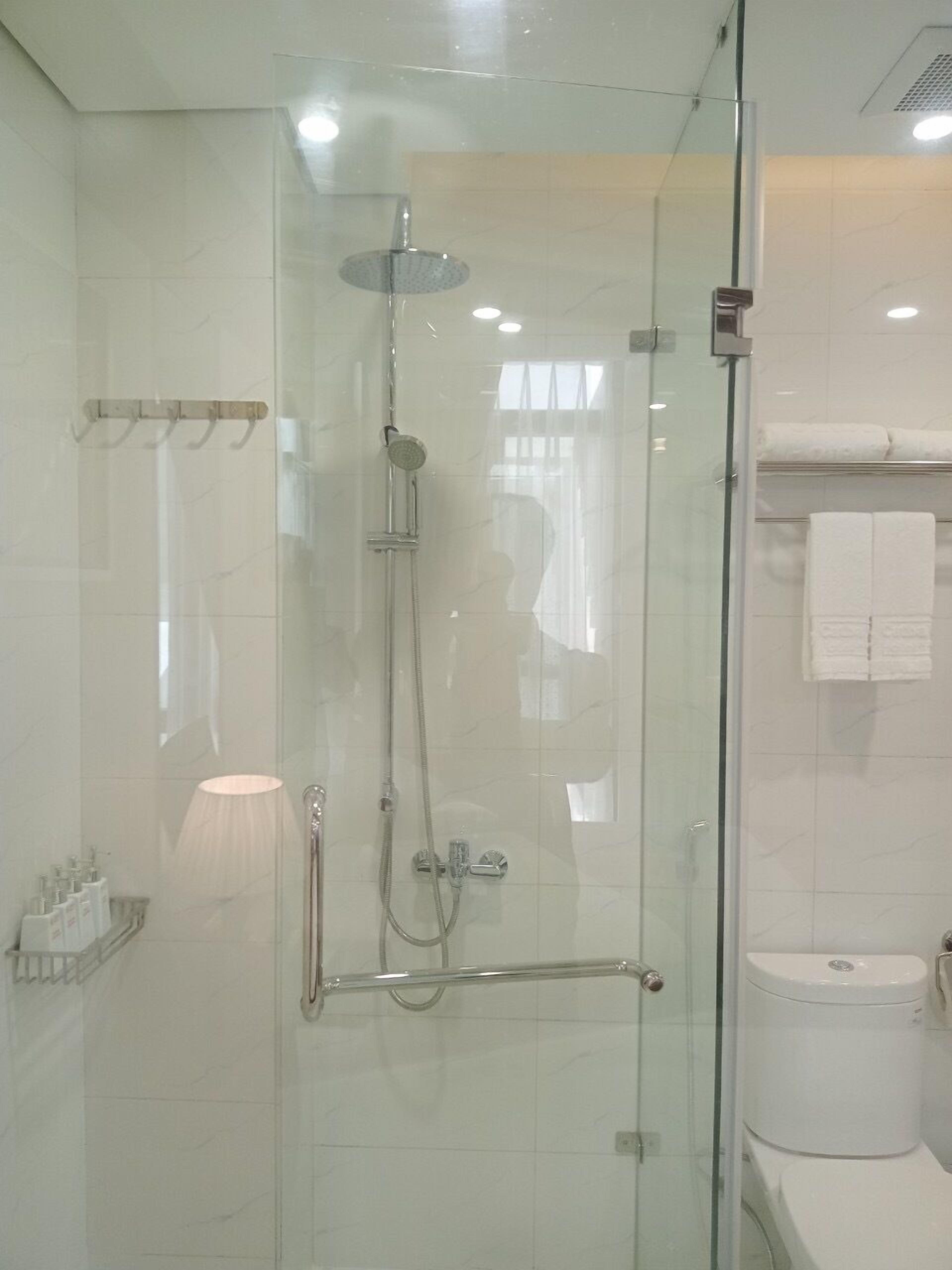 A modern bathroom with a glass-enclosed shower, a toilet, and a towel rack.