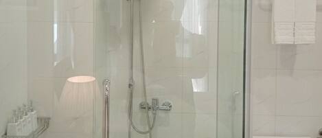 A modern bathroom with a glass-enclosed shower, a toilet, and a towel rack.
