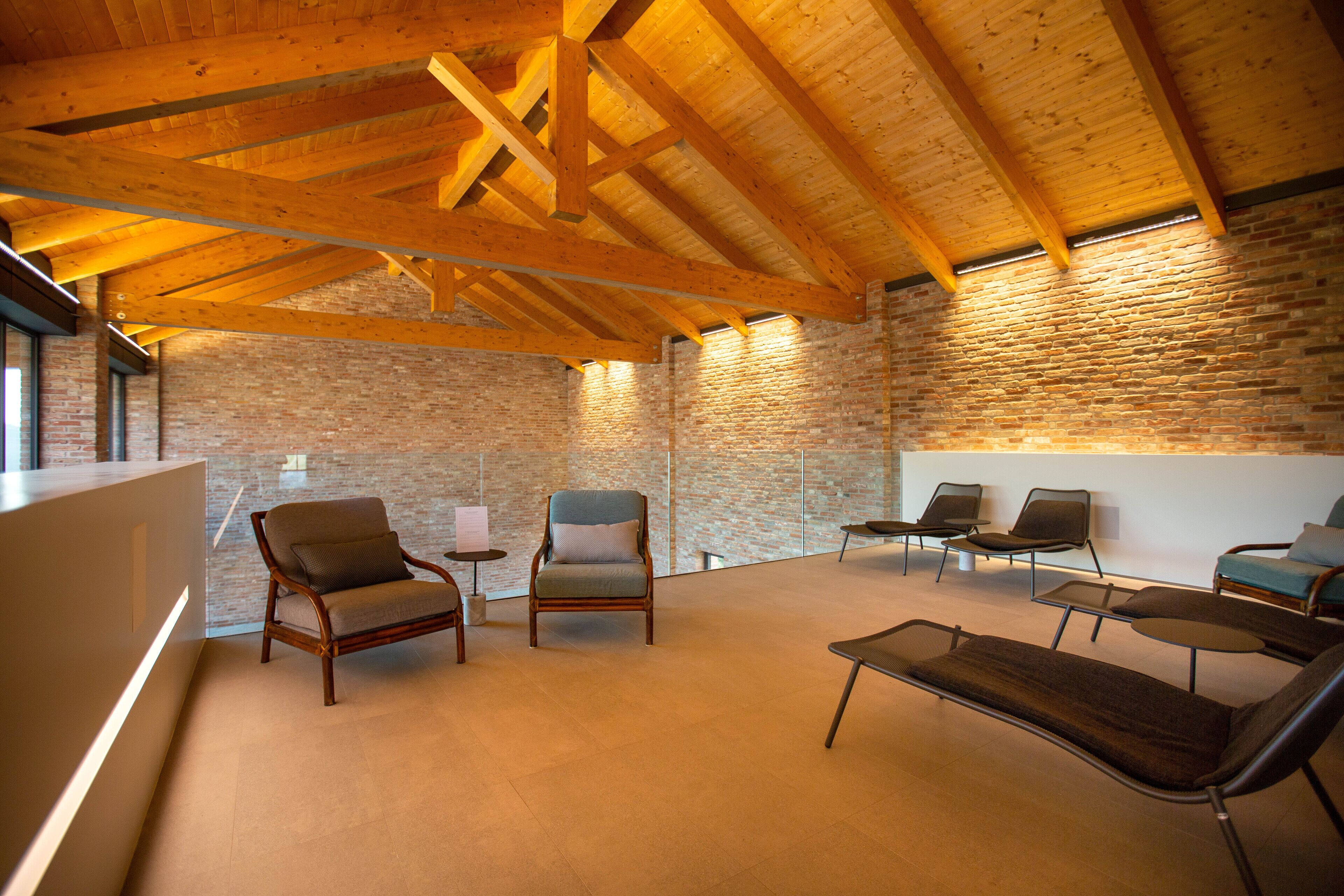 Un'ampia hall con soffitto in legno a volta, pareti in mattoni e diverse zone relax.