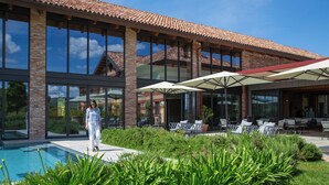 Un edificio moderno con piscina, mobiliario exterior y un jardín bien cuidado.