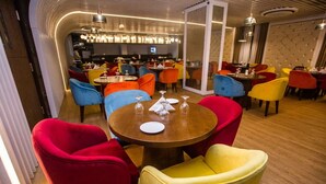 A dining area with round tables and colorful chairs. - Grand River View Hotel (Rajshahi)