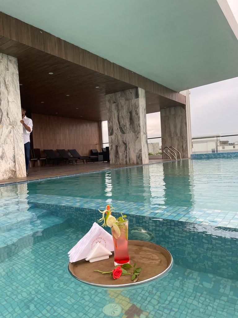 A pool area with a drink on a tray, a rose, and a napkin.