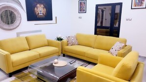 Una sala de estar con dos sofás amarillos, una mesa de centro y obras de arte en las paredes.