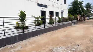 Un edificio con fachada blanca, cerca metálica negra y camino de grava.