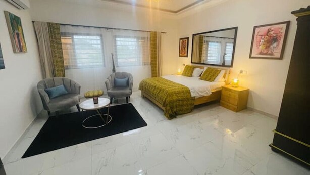 Habitación de hotel con cama, dos sillones, una mesita, una mesita de noche y un espejo.