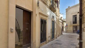 Un vicolo stretto con lastricato in pietra, una porta in legno e un cancello in metallo.