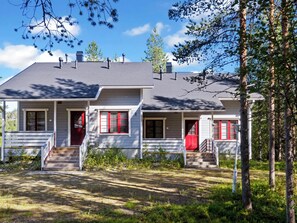 A two-story house with a front porch, a red door, and a chimney.