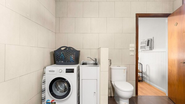 A compact, modern bathroom with a Bosch washing machine, a sink, and a toilet.