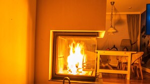 A cozy living room with a fireplace, a wicker basket, and a wooden table. - Vacation home with 80 sqm - on Ballumweg on Sylt (Sylt)