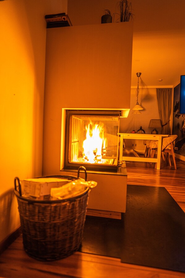 A cozy living room with a fireplace, a wicker basket, and a wooden table.