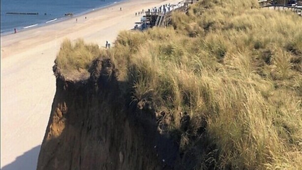 A beach with a cliff and grassy area in the foreground. - Vacation home with 80 sqm - on Ballumweg on Sylt (Sylt)