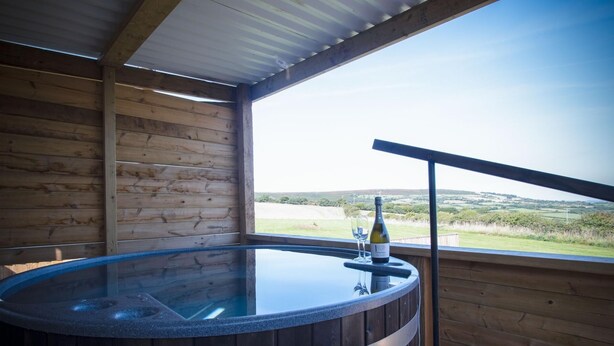 Una cabaña de madera con jacuzzi y una mesa de vidrio.
