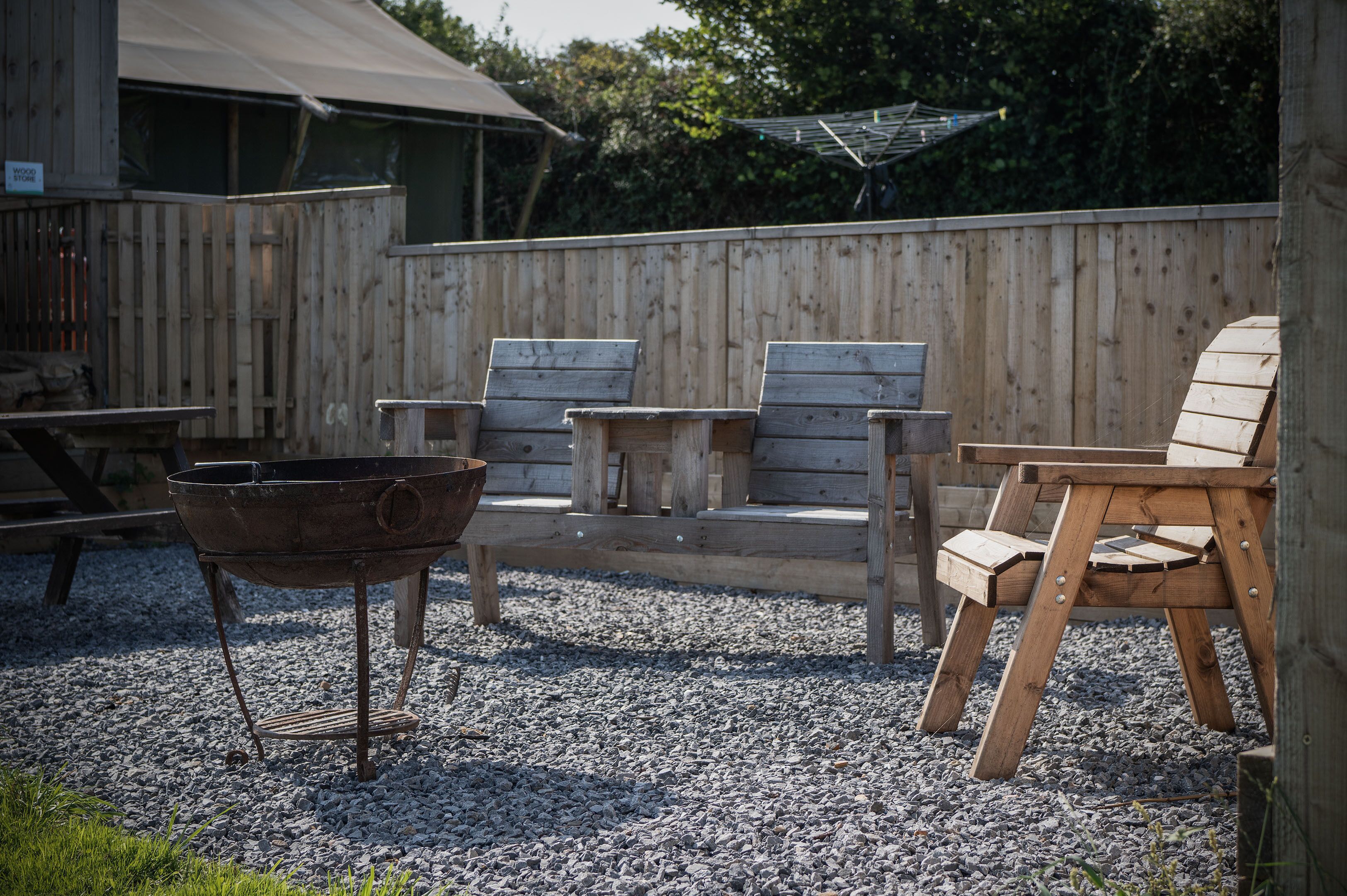 Een houten terras met een barbecue, een tafel en twee Adirondack stoelen.