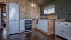 Uma cozinha compacta com painéis de madeira, geladeira, forno, pia e armários.