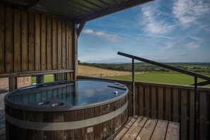 A wooden deck with a hot tub and a view of a grassy field. - Three Cliffs Glamping Tent - Llangennith (Swansea)