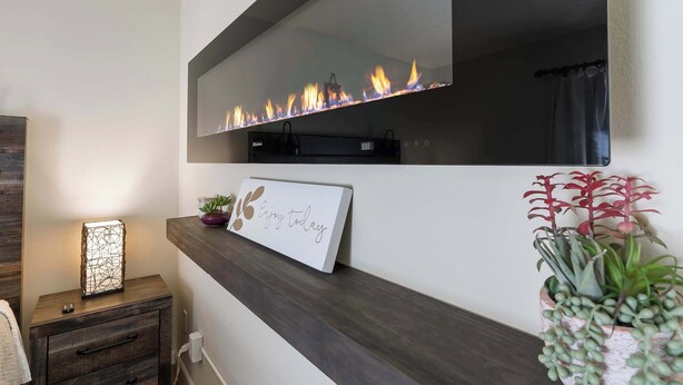 Un salon moderne avec une cheminée, une petite table sur laquelle est posé un panneau, et une plante en pot.