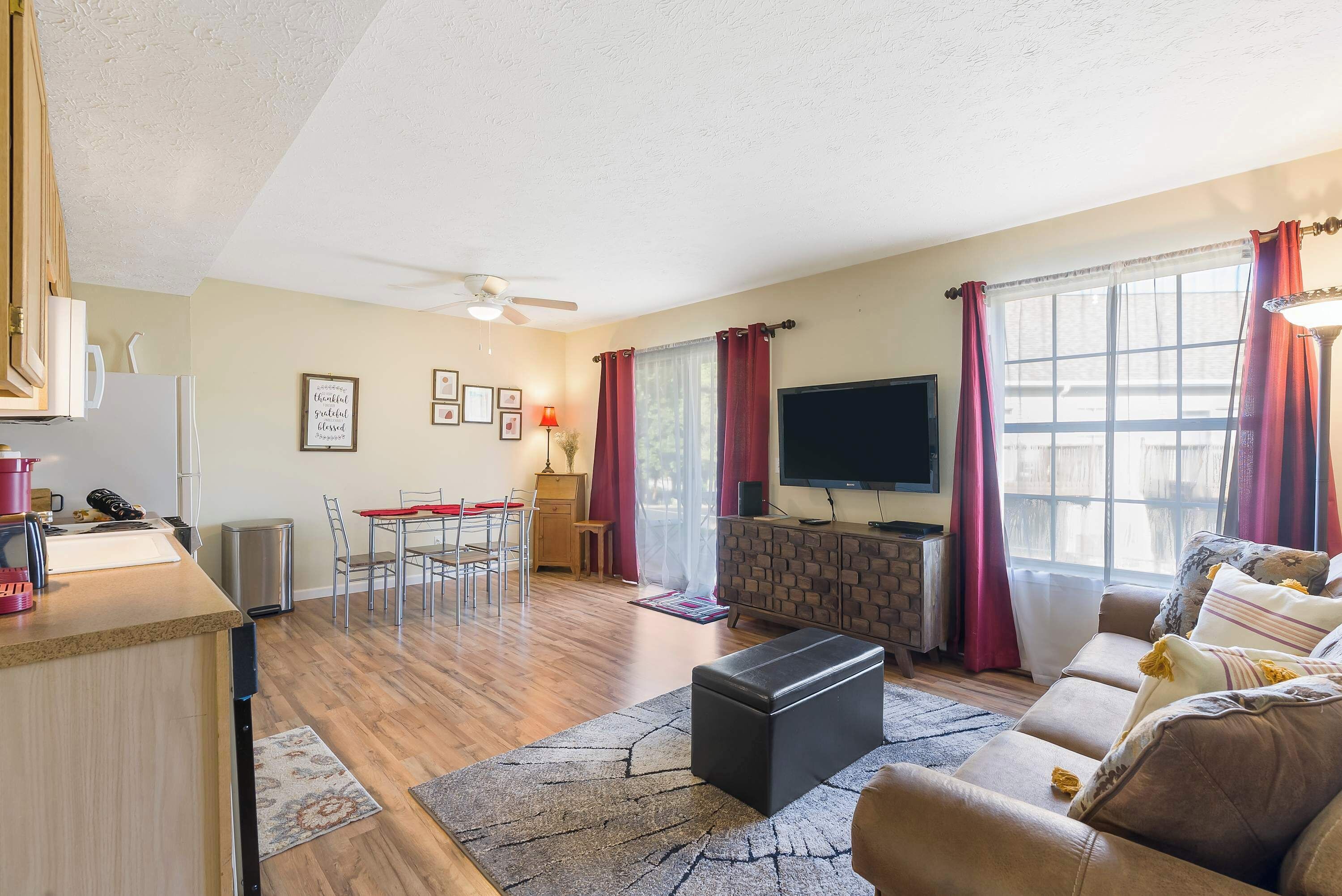 A living room with a sofa, a coffee table, a TV, a fireplace, and a dining area with chairs and a table.