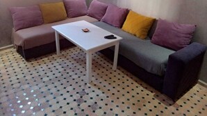 Une pièce comprenant un canapé, une petite table blanche et un sol à motifs.