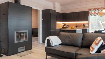 A modern living room with a sofa, a fireplace, and a kitchen area with a window.