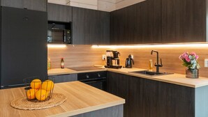 Eine moderne Küche mit dunklen Holzschränken, einer zentralen Kochinsel mit gewebter Unterlage und einem Edelstahl-Spülbecken.